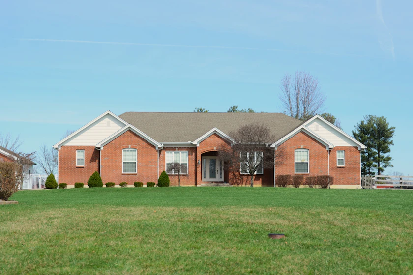 A suburban street of one-story brick homes with maturing shade trees between the sidewalks and porches